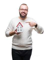Young caucasian real state agent man holding house isolated background very happy pointing with...