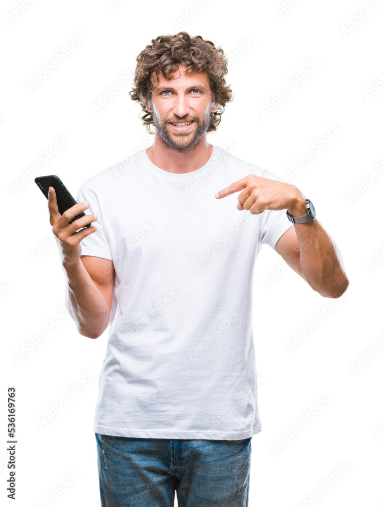 Poster Handsome hispanic man model sending message texting using smartphone over isolated background with surprise face pointing finger to himself