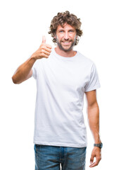 Handsome hispanic model man over isolated background doing happy thumbs up gesture with hand. Approving expression looking at the camera with showing success.