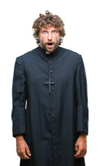 Handsome hispanic catholic priest man over isolated background afraid and shocked with surprise expression, fear and excited face.
