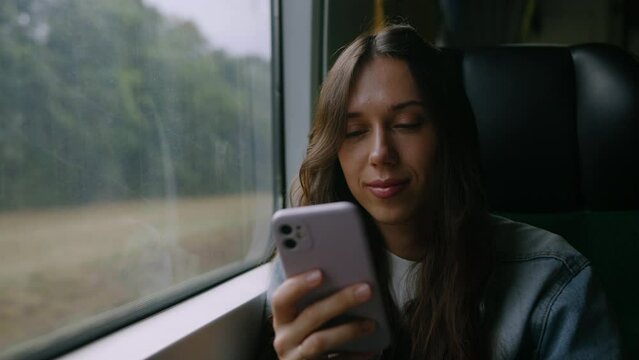 A young woman reads the news on her phone while traveling by train. Comfortable long-distance train