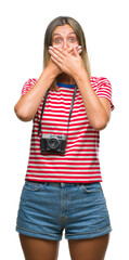 Young beautiful woman taking pictures using vintage photo camera over isolated background shocked covering mouth with hands for mistake. Secret concept.