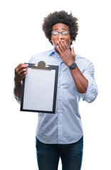 Afro american man holding clipboard over isolated background cover mouth with hand shocked with shame for mistake, expression of fear, scared in silence, secret concept