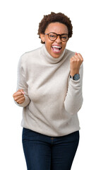 Young beautiful african american woman wearing glasses over isolated background very happy and excited doing winner gesture with arms raised, smiling and screaming for success. Celebration concept.