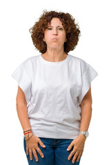 Beautiful middle ager senior woman wearing white t-shirt over isolated background puffing cheeks with funny face. Mouth inflated with air, crazy expression.