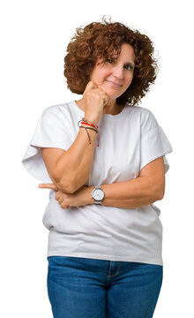 Beautiful middle ager senior woman wearing white t-shirt over isolated background with hand on chin thinking about question, pensive expression. Smiling with thoughtful face. Doubt concept.