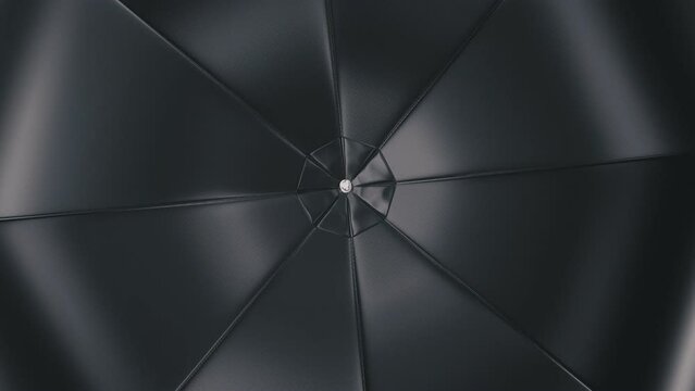 Realistic looping 3D animation of the spinning black umbrella or parasol rendered in UHD as motion background
