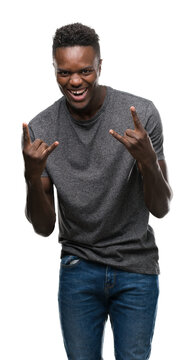 Young african american man wearing grey t-shirt shouting with crazy expression doing rock symbol with hands up. Music star. Heavy concept.