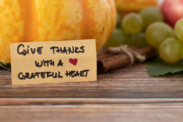 Give thanks with a grateful heart, a handwritten text on a vintage card with various autumn fruit...