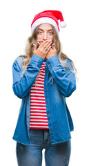 Beautiful young blonde woman wearing christmas hat over isolated background shocked covering mouth with hands for mistake. Secret concept.