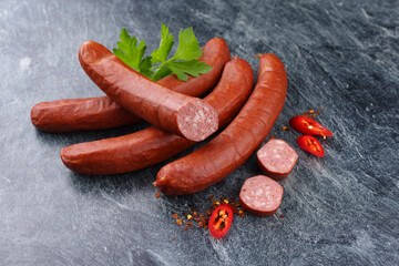 Traditional raw Bavarian spicy bratwurst with chili offered as close-up on rustic grey board with...