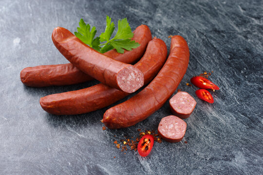 Traditional raw Bavarian spicy bratwurst with chili offered as close-up on rustic grey board with text space