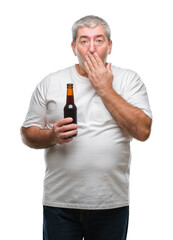 Handsome senior man drinking beer bottle over isolated background cover mouth with hand shocked...