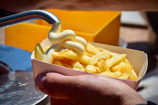 Pouring mayonnaise over French fries