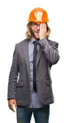 Young handsome architec man with long hair wearing safety helmet over isolated background covering one eye with hand with confident smile on face and surprise emotion.