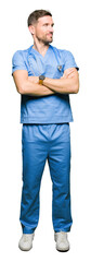 Handsome doctor man wearing medical uniform over isolated background smiling looking to the side with arms crossed convinced and confident