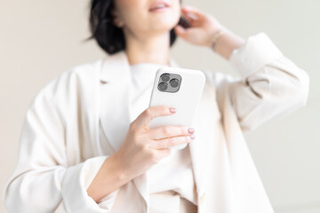 Close-up of the camera. A modern smartphone with three cameras. An unrecognizable woman in light clothes holds a phone in her hand and straightens her hair.