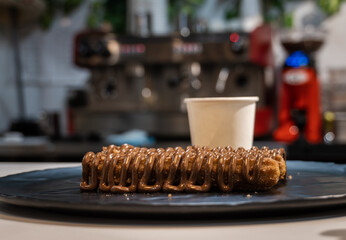 Churros with sugar and chocolate sauce, on a black plate.