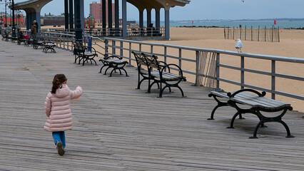 a young girl is running around the boardwalk in winter