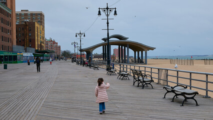a young girl is running around the boardwalk in winter - Powered by Adobe