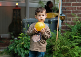 a young boy is Playing with a ball in the backyard