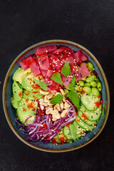 Top view on poke salad with tuna and green vegetable in the bowls on gray background. Copy space.