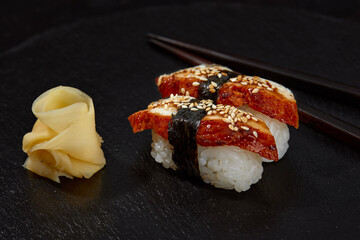 Sushi with smoked eel and sesame seeds on a black background. Japanese dish Unagi sushi.