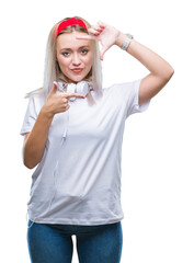 Young blonde woman wearing headphones listening to music over isolated background smiling making frame with hands and fingers with happy face. Creativity and photography concept.