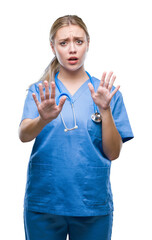 Young blonde surgeon doctor woman over isolated background afraid and terrified with fear...