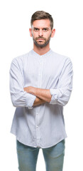 Young handsome man over isolated background skeptic and nervous, disapproving expression on face with crossed arms. Negative person.