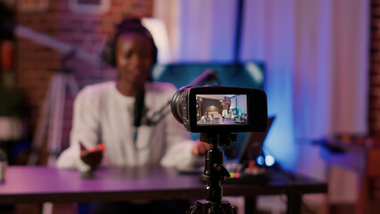 Selective focus on african american woman influencer talking in front of digital camera recording...