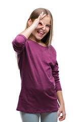 Young beautiful girl over isolated background doing ok gesture with hand smiling, eye looking through fingers with happy face.