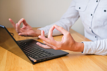 Man at laptop holding hands with om gesture closeup