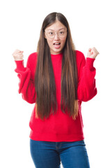 Young Chinese woman over isolated background wearing glasses celebrating surprised and amazed for success with arms raised and open eyes. Winner concept.