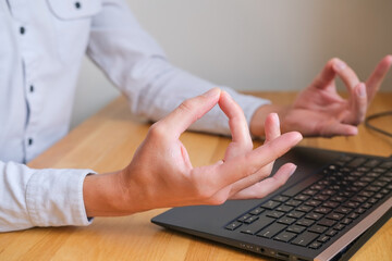 Fototapeta premium Close up of a person holds hands with om gesture while working on a laptop computer