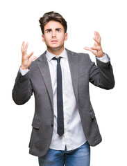 Young business man wearing suit and tie over isolated background crazy and mad shouting and yelling with aggressive expression and arms raised. Frustration concept.