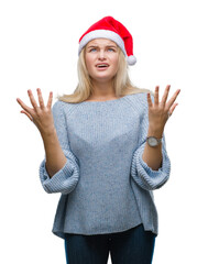 Young caucasian woman wearing christmas hat over isolated background crazy and mad shouting and yelling with aggressive expression and arms raised. Frustration concept.