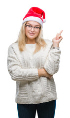 Young caucasian woman wearing christmas hat over isolated background with a big smile on face, pointing with hand and finger to the side looking at the camera.