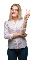 Young caucasian business woman wearing glasses over isolated background smiling with happy face winking at the camera doing victory sign. Number two.