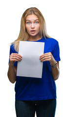 Fototapeta na wymiar Young caucasian woman holding blank paper sheet over isolated background scared in shock with a surprise face, afraid and excited with fear expression