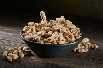 Dried peanuts in a bowl on a wooden table.