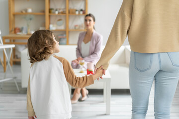 Obraz premium Concept of a happy healthy relationship between children and parents. Go to a family psychologist. Mom holds the hand of her not quite year old son.