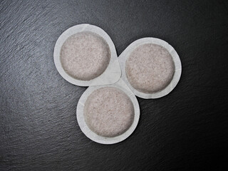 Coffee pods on a black slate board.