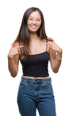 Fototapeta premium Young asian woman wearing glasses over isolated background looking confident with smile on face, pointing oneself with fingers proud and happy.