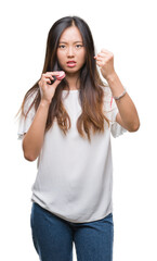 Obraz na płótnie Canvas Young asian woman eating pink macaron sweet over isolated background annoyed and frustrated shouting with anger, crazy and yelling with raised hand, anger concept