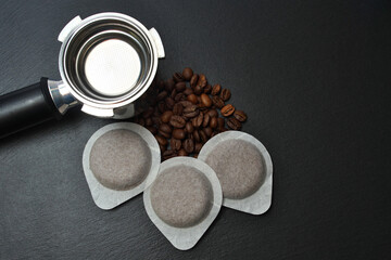 Coffee pods, coffee beans, horn-holder on a black slate board.