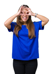 Obraz na płótnie Canvas Young beautiful brunette woman wearing blue t-shirt over isolated background doing ok gesture like binoculars sticking tongue out, eyes looking through fingers. Crazy expression.
