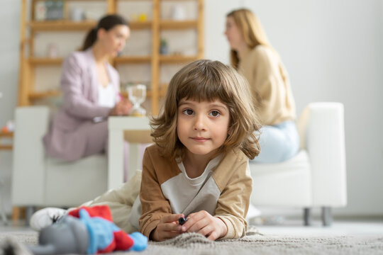Close-up of a boy. Mom and son at a consultation with a child psychologist. The boy plays with toys sitting on the floor. Family relationships.