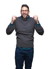 Fototapeta premium Young handsome man wearing glasses over isolated background excited for success with arms raised celebrating victory smiling. Winner concept.