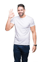 Naklejka premium Young man wearing casual white t-shirt over isolated background smiling positive doing ok sign with hand and fingers. Successful expression.